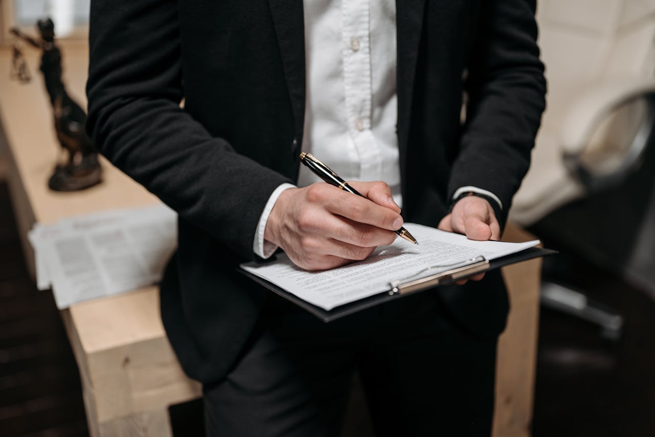 services-02 Business professional signing a contract on a clipboard at the office.